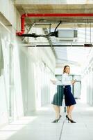 Young woman with digital tablet standing in the modern office hallway photo