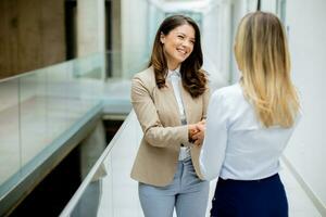 Two young business women handshaking  in the office hallway photo