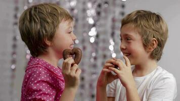 twee kinderen Holding omhoog snoepgoed en eten het video