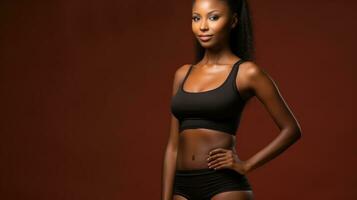 Beautiful young african american woman in sportswear on brown background. photo