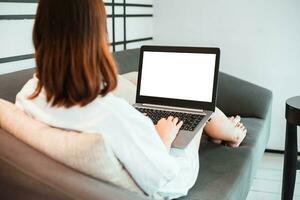 young woman working on laptop computer while sitting at the living room. work from home concept photo