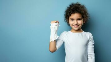 pequeño niña con roto brazo en yeso vendaje en azul antecedentes. foto