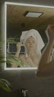 ein Frau im ein Handtuch ist suchen beim Sie selber im das Spiegel video