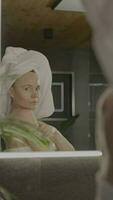 a woman in a towel is looking at herself in the mirror video