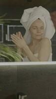 un mujer en un toalla es mirando a sí misma en el espejo video