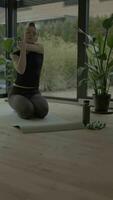 a woman is doing yoga in front of a plant video