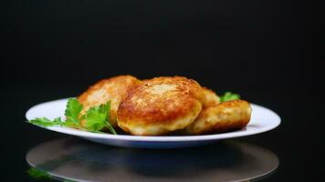 Cooked fried fish cutlets in a plate with herbs, isolated on a black background. video