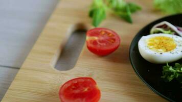 boiled eggs with salted red fish, herbs and seasonings in a plate on a wooden table. video