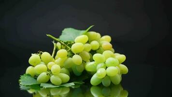 A bunch of ripe green grapes with leaves, isolated on a black background. video