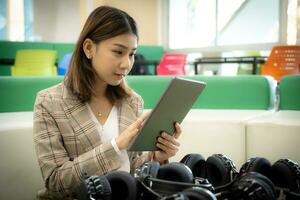 Beautiful asian businesswoman sitting and pressing tablet to pro photo