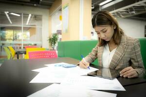 hermosa asiático mujer de negocios es enfoque en documentos en el empresa con confianza. foto