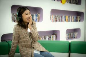 Beautiful asian in close-up shot is shown watching a movie while wearing headphones with a joyful expression. photo