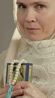 a woman in a hijab holding a book and a prayer beads video