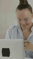 a woman in glasses talking on the phone while using a laptop video