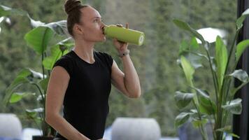 une femme est en buvant de une vert bouteille video