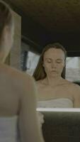 a woman in a towel is looking at herself in the mirror video