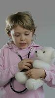 un' giovane ragazzo nel un' rosa camicia Tenere un' bianca orsacchiotto orso video