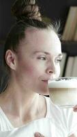 a woman is drinking from a cup of coffee while standing beside the window video