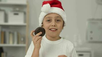 un chico en un Papa Noel sombrero comiendo un chocolate pastel video