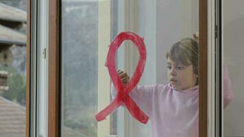 un niño con un rojo cinta en el ventana video