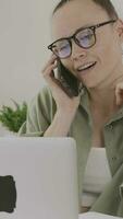 a woman in glasses talking on the phone while using a laptop video