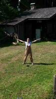 a woman in overalls standing in the yard with his arms outstretched video