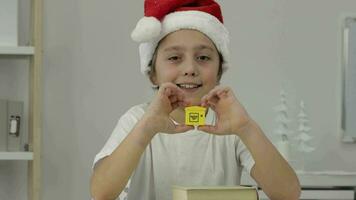 un chico en un Papa Noel sombrero participación un amarillo juguete video