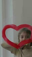 a child drawing a heart shaped on a glass video