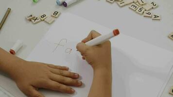 un' bambino scrittura su un' pezzo di carta con un' marcatore video