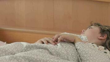 uma pequeno menina deitado dentro cama com dela mão em dela estômago video