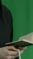 a person in a black robe praying with a prayer beads and prayer book video