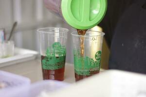 Hand of Indonesian street vendor prepares a glass of iced photo