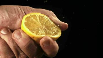 hand- knijpt citroen sap met spatten. gefilmd Aan een hoge snelheid camera Bij 1000 fps. hoog kwaliteit full HD beeldmateriaal video