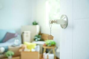 Moving house, relocation. The key was inserted into the door of the new house, inside the room was a cardboard box containing personal belongings and furniture. move in the apartment or condominium photo