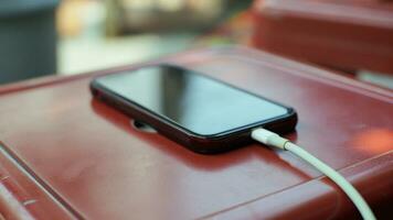 de cerca de un móvil teléfono siendo cargado en un rojo metal mesa en un cafetería. foto