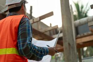 inspector or engineer is inspecting construction and quality assurance new house using a blue print. Engineer or architects or contactor work to build the house before handing it over to the homeowner photo
