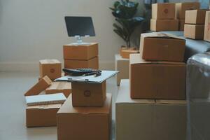 Startup SME small business entrepreneur of freelance Asian woman using a laptop with box Cheerful success Asian woman her hand lifts up online marketing packaging box and delivery SME idea concept photo