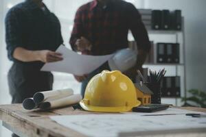 Close up of civil male engineer asian working on blueprint architectural project at construction site at desk in office. photo