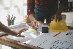 Close up of civil male engineer asian working on blueprint architectural project at construction site at desk in office. photo