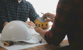 Close up of civil male engineer asian working on blueprint architectural project at construction site at desk in office. photo