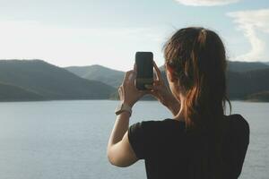 Young woman traveler in casual clothes with backpack from back on background of beautiful view on mountains photo