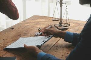 Justice and Law concept. Legal counsel presents to the client a signed contract with gavel and legal law or legal having team meeting at law firm in background photo