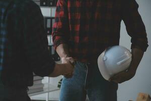 primer plano de un ingeniero civil asiático que trabaja en un proyecto arquitectónico de planos en el sitio de construcción en el escritorio de la oficina. foto