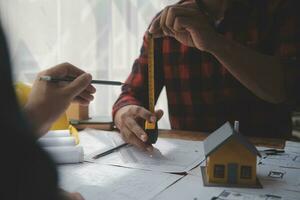 Close up of civil male engineer asian working on blueprint architectural project at construction site at desk in office. photo