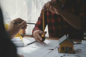 primer plano de un ingeniero civil asiático que trabaja en un proyecto arquitectónico de planos en el sitio de construcción en el escritorio de la oficina. foto