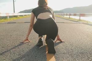 Young lady running on a rural road during sunset photo