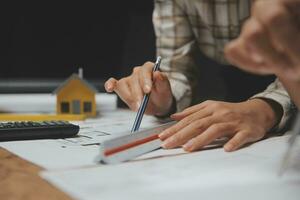 Team of multiethnic architects working on construction plans in meeting room. Engineers discussing on project in office. Mature businessman and woman standing around table working on blueprint. photo