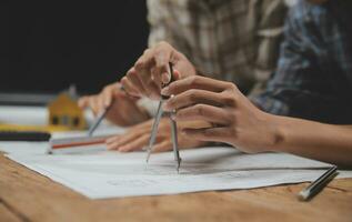 Team of multiethnic architects working on construction plans in meeting room. Engineers discussing on project in office. Mature businessman and woman standing around table working on blueprint. photo