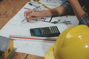 Team of multiethnic architects working on construction plans in meeting room. Engineers discussing on project in office. Mature businessman and woman standing around table working on blueprint. photo