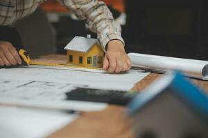 Team of multiethnic architects working on construction plans in meeting room. Engineers discussing on project in office. Mature businessman and woman standing around table working on blueprint. photo